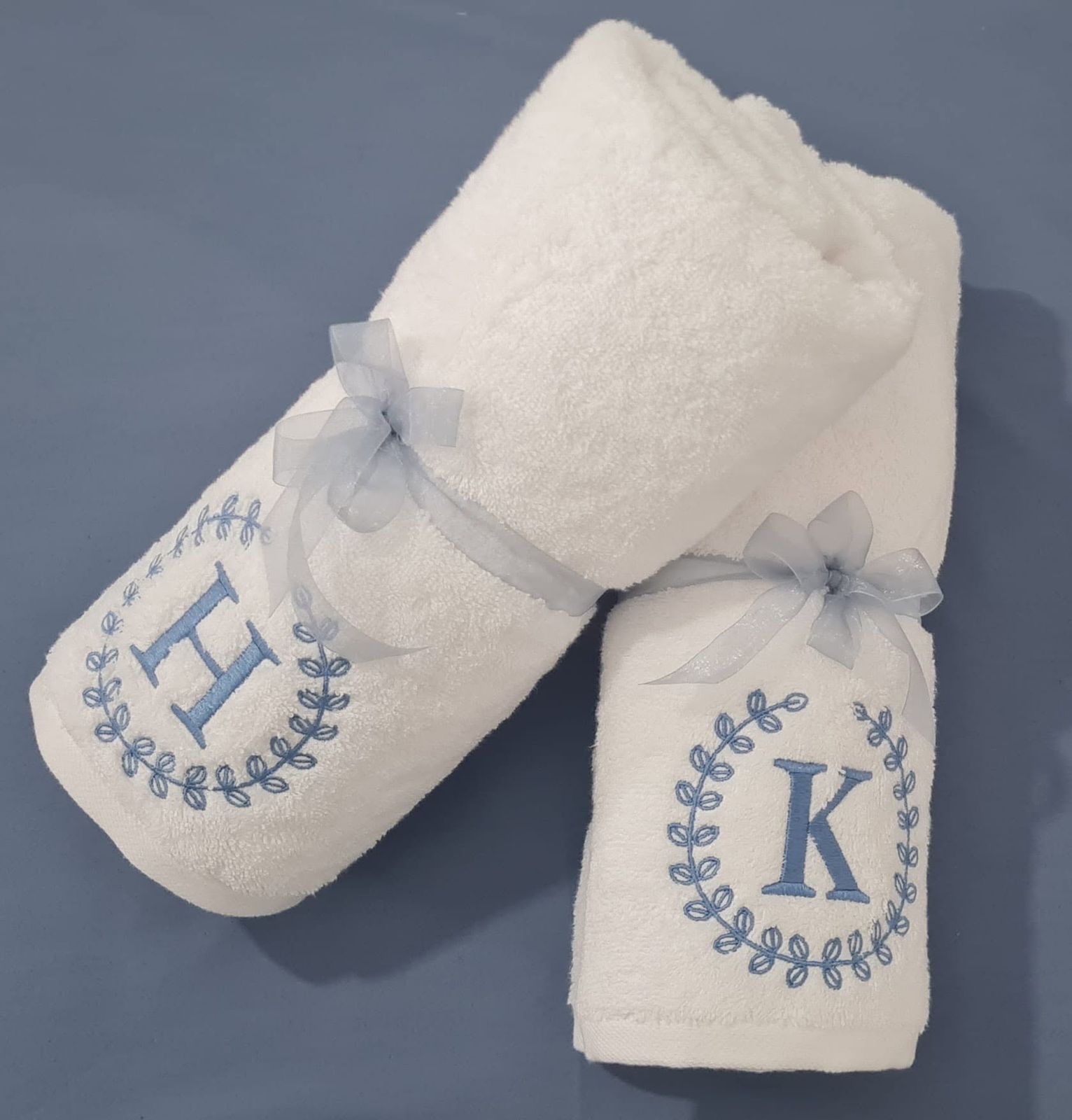 White Melchiah towels embroidered with single initials framed by a wreath