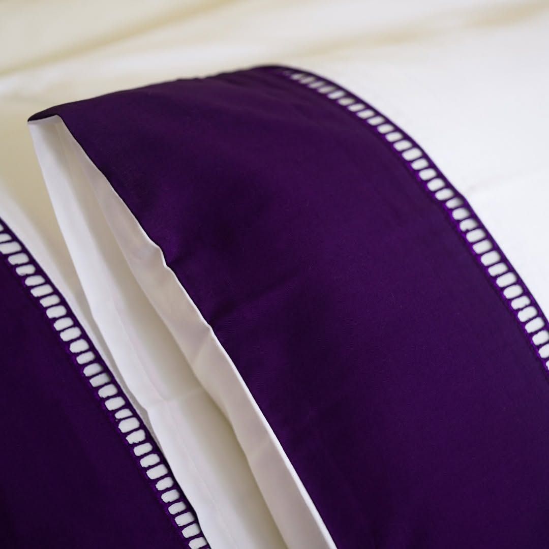 Deep aubergine Melchiah bedding finished with a scalloped white trim