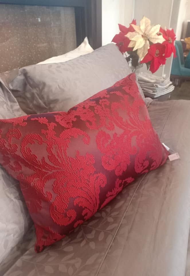 Crimson jacquard Melchiah cushion styled against soft neutral bedding