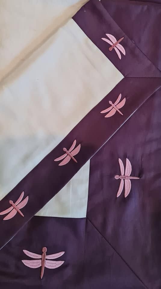 Rich plum Melchiah table linen embroidered with a dragonfly motif